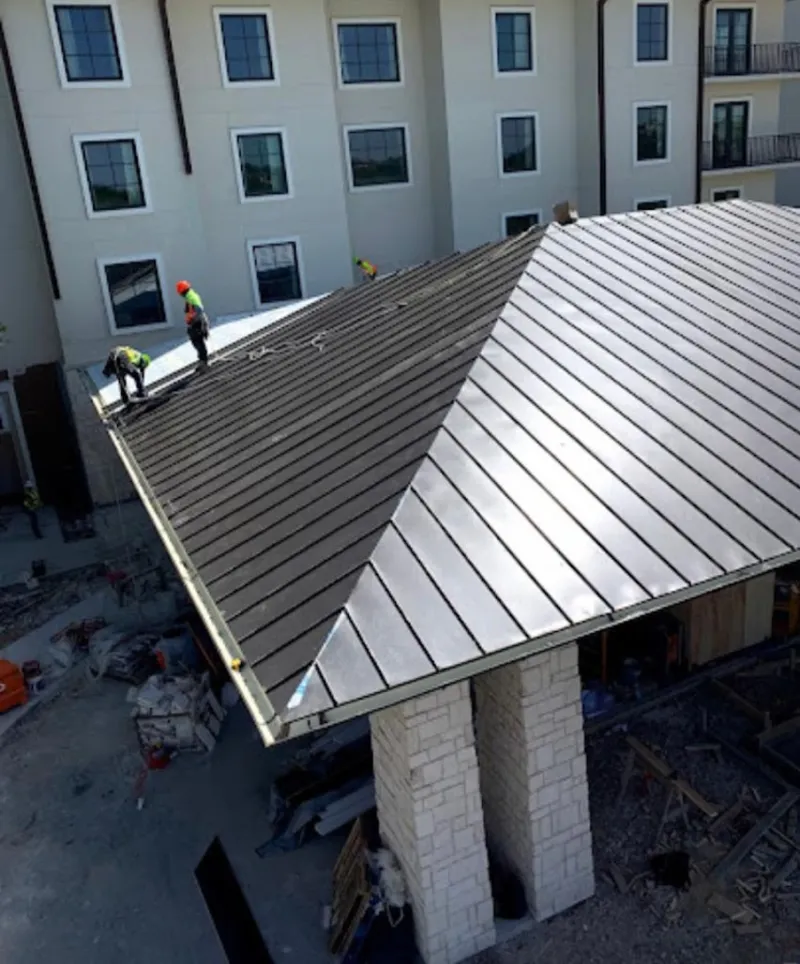 Crew installing standing seam metal roof panels on a commercial project in Maple Valley